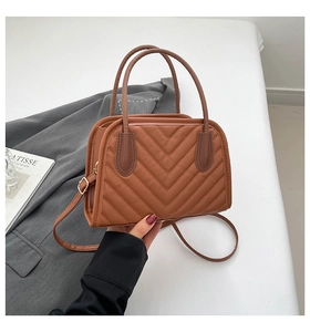 Detail of brown V-quilted handbag with gold buckles and round handles for workwear