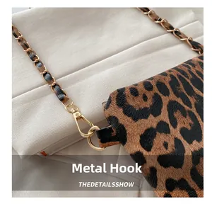 Detailed macro view of the gold lobster clasp and leopard print leather shoulder strap
