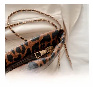 Detailed close-up of leopard print handbag showing the smooth gold-tone zipper and chain strap