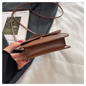Detail view of the stitching and magnetic closure on a brown leather crossbody bag