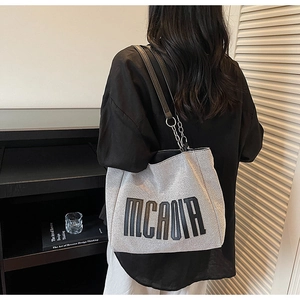 Detail of grey canvas tote with black MCAOR text and leather metal chain strap