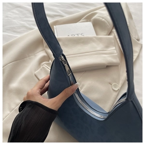 Detailed texture of blue matte suede hobo bag with sleek silver zipper and shoulder strap