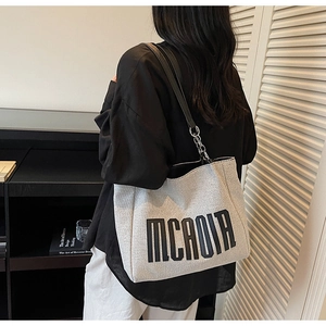 Detailed view of grey canvas tote bag with black letter print and chain strap detail