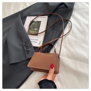 Detail of a brown PU leather mini handbag with top handle and adjustable shoulder strap