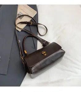 Detail of vintage brown textured leather handbag with brass buckle and long shoulder strap