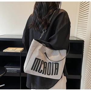Detail of canvas tote bag with black MCROIA print and leather chain shoulder strap