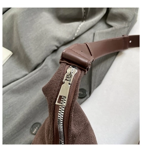 Detailed macro shot of silver zipper and brown suede texture on a vintage shoulder bag
