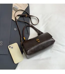 Detail of dark brown leather handbag with gold metal clasp and adjustable strap
