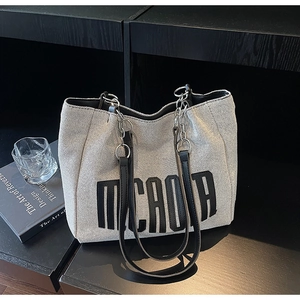 Close-up of canvas tote bag with black letter print and chain leather shoulder strap
