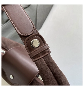 Detail of vintage brown shoulder bag showing stitching and silver rivet hardware