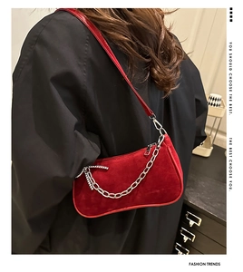 Model wearing red suede baguette bag with chunky silver chain and black outfit