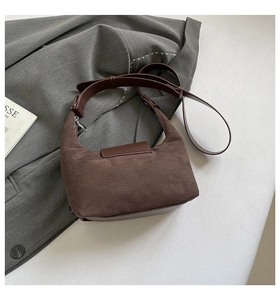 Detailed close-up of dark brown suede crescent bag with textured leather strap