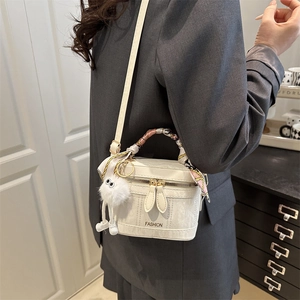 Detail of white mini square handbag with fashion text, silk scarf and plush monster charm