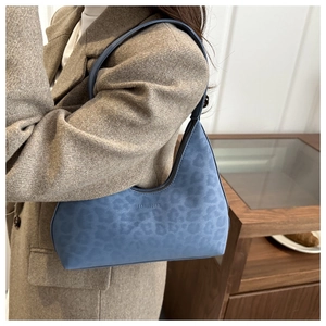 Detailaufnahme der blauen Schultertasche mit Leopardenmuster und Wildledertextur