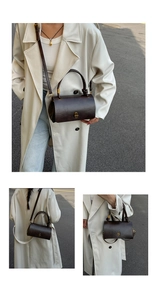 Detail of dark brown cylindrical crossbody bag with gold buckle and knotted handle
