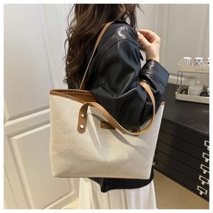 Chic cream canvas tote bag with brown leather handles worn by model in casual style