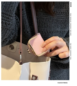 Pink lychee grain leather mini clasp pouch attached as a charm to a white tote bag