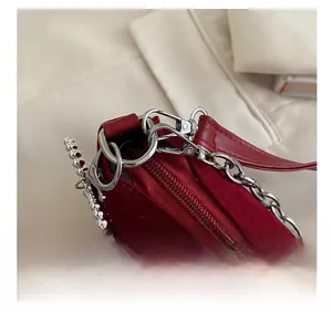 Detailed close-up of red velvet handbag with silver hardware and bead chain decor