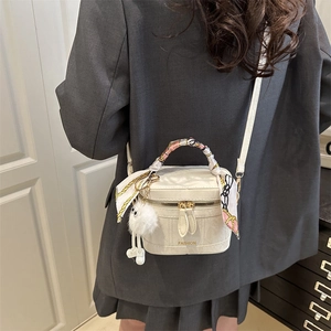 White quilted handbag with scarf-wrapped handle and plush charm detail on display