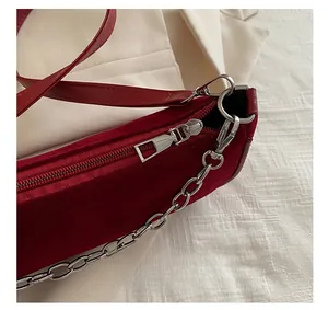Detail of red velvet bag showing silver metal chain and smooth zipper closure