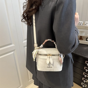 Close-up of white leather handbag with silk scarf wrapped handle and fashion lettering