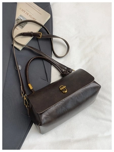 Detail of dark brown retro handbag featuring gold twist lock and smooth faux leather texture
