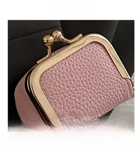 Detailed macro view of pink pebbled leather coin purse with golden kiss-lock clasp