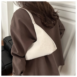 Minimalist off-white triangular leather shoulder bag styled on a brown blazer outfit