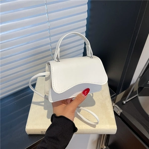Chic white mini crossbody bag with a scalloped flap and smooth faux leather finish