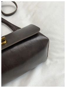 Detail of dark brown vintage faux leather texture and bronze metal twist lock closure