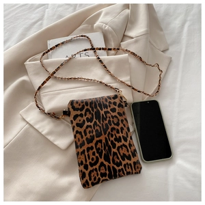 Detail of leopard print mini crossbody bag with golden chain strap on a blazer