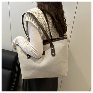 Macro shot of large canvas tote bag with brown leather straps and rivet detail