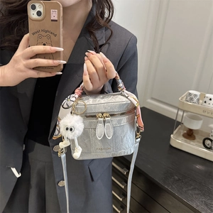 Detail of silver crinkled leather handbag with silk scarf handle and plush monster charm