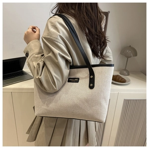 Close-up of canvas tote bag with black leather trim shown in a professional lifestyle setting