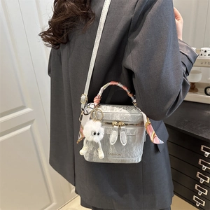 Detail of silver pleated handbag with fashion text, silk scarf handle, and cute plush charm