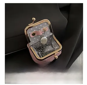 Interior view of pink lychee leather kiss-lock pouch showing baroque pearl necklace storage