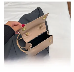 Detail view of the beige crossbody bag interior with golden magnetic buckle and black lining