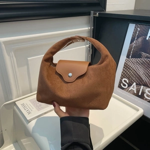 Brown vintage suede handbag with silver metal buckle held by model in artistic studio