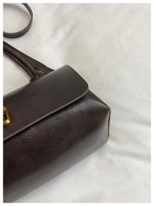 Detail of dark brown leather handbag showing fine stitching and smooth glossy texture