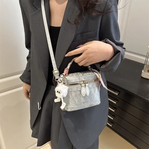 Detail of silver pleated handbag with scarf, plush charm, and fashion logo text