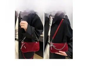 Detail showing red velvet underarm bag with rhinestone bow and silver chain strap