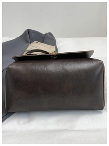Detail of dark brown retro leather handbag featuring vintage oil-wax texture and flap closure