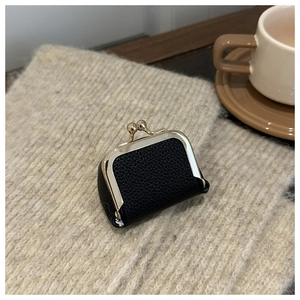 Close-up of black lychee leather mini bag with gold clasp on beige knit textile