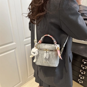 Silver wrinkled crossbody bag with a pink silk scarf handle and plush monster charm