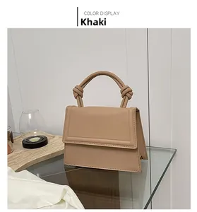Detail of the khaki trapezoid handbag showing knotted handle and precise stitching