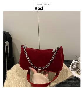 Detail view of red suede underarm bag with silver chain strap and zipper closure