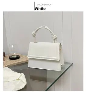 Detail of white leather shoulder bag featuring unique artistic knotted handle design