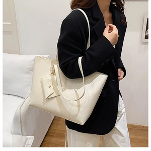 Close-up of cream white tote bag with vertical stitching and mini hanging pouch detail