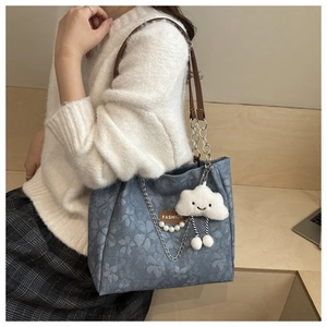 Blue floral denim shoulder bag with leather strap and cloud charm shown on model
