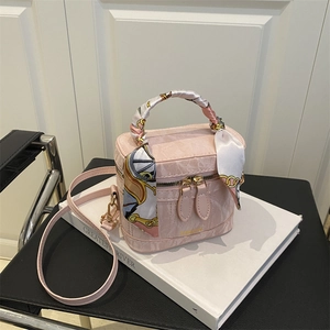 Detail of light pink cylindrical handbag with marble texture and silk scarf handle